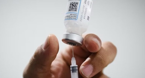 Flacon de vaccin et seringue tenus en main